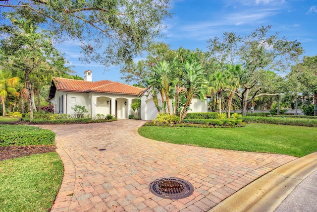 mediterranean / spanish home featuring a garage and a front lawn