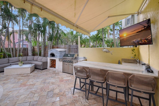 view of patio / terrace featuring an outdoor living space, a grill, exterior kitchen, and a wet bar