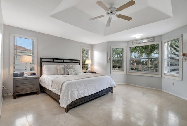 bedroom with a raised ceiling, multiple windows, and ceiling fan