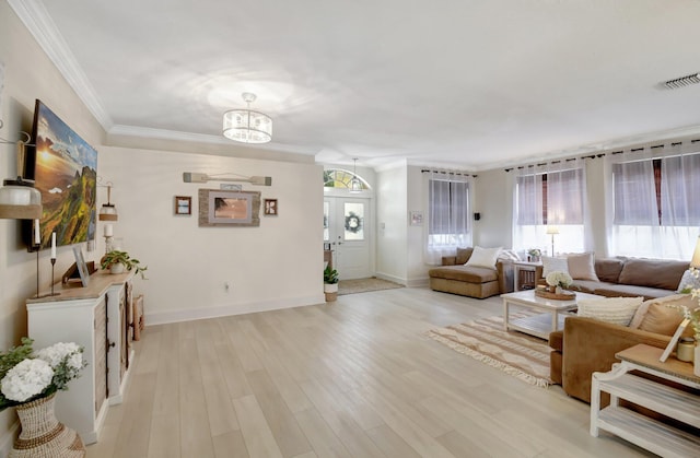 living room with light wood-type flooring, an inviting chandelier, and ornamental molding