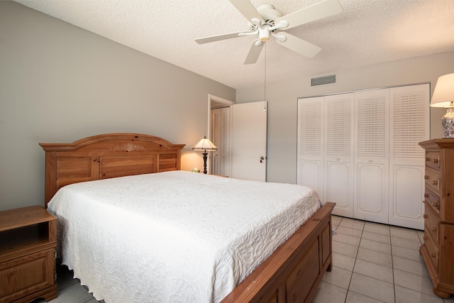 tiled bedroom featuring ceiling fan, a textured ceiling, and a closet