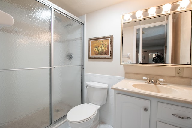 bathroom featuring toilet, a shower with door, and vanity