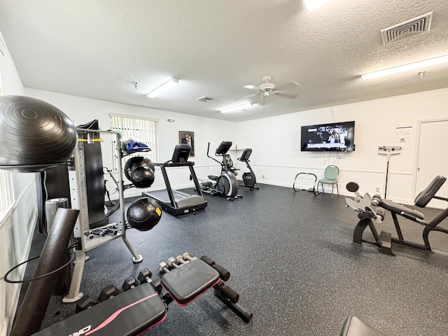 gym featuring a textured ceiling and ceiling fan