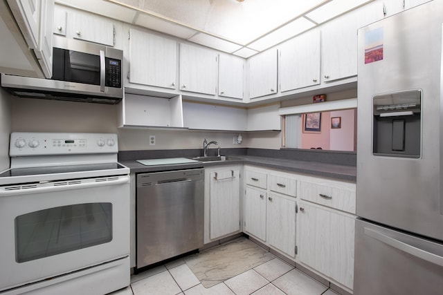 kitchen with light tile patterned flooring, appliances with stainless steel finishes, white cabinetry, and sink