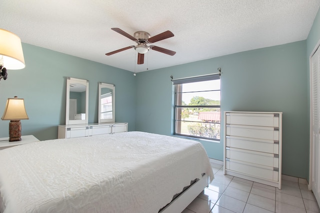 tiled bedroom featuring a textured ceiling, ceiling fan, and a closet