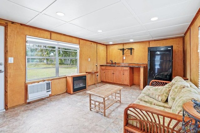 living room featuring heating unit, wood walls, and sink