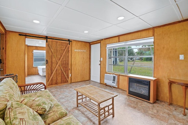 living room with a barn door, heating unit, and wood walls