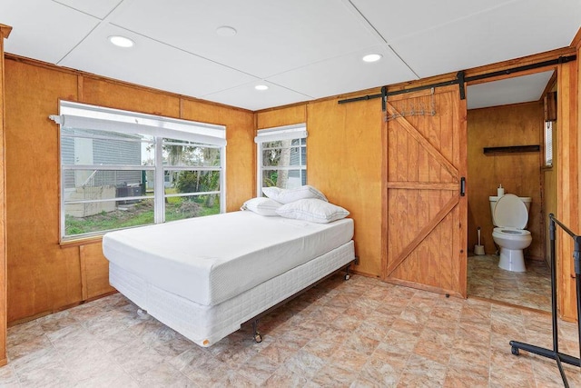 bedroom with wood walls and a barn door