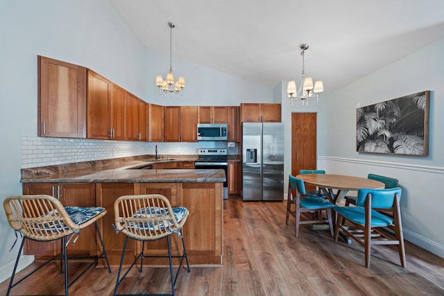 kitchen featuring pendant lighting, appliances with stainless steel finishes, kitchen peninsula, and a notable chandelier