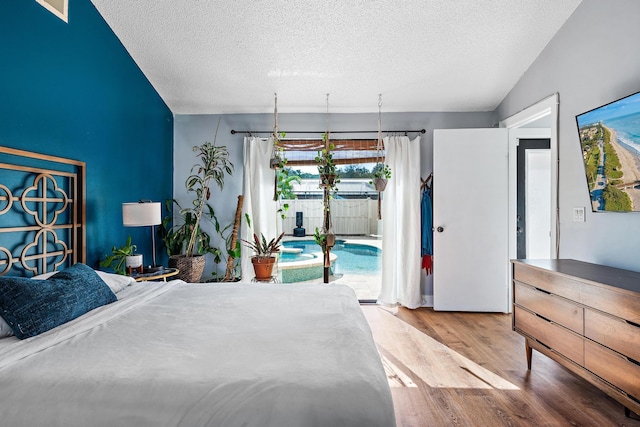 bedroom with wood-type flooring, access to exterior, and a textured ceiling