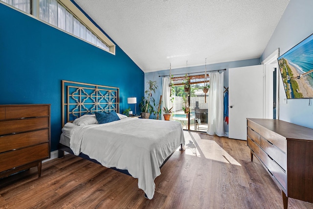 bedroom with hardwood / wood-style flooring, access to exterior, vaulted ceiling, and a textured ceiling