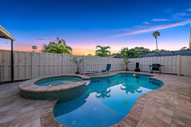 pool at dusk with grilling area, a patio, and an in ground hot tub