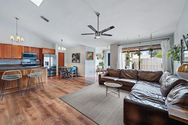 living room featuring high vaulted ceiling, wood-type flooring, and ceiling fan with notable chandelier