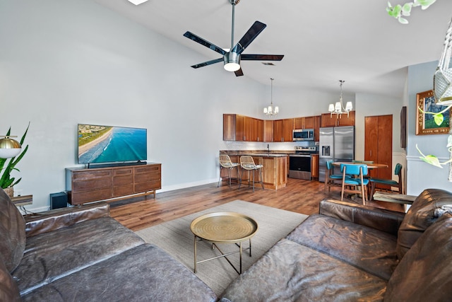 living room with wood-type flooring, sink, ceiling fan with notable chandelier, and high vaulted ceiling