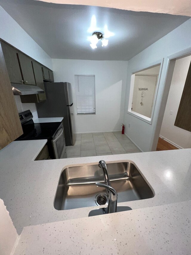 kitchen featuring stainless steel appliances, light countertops, a sink, and under cabinet range hood