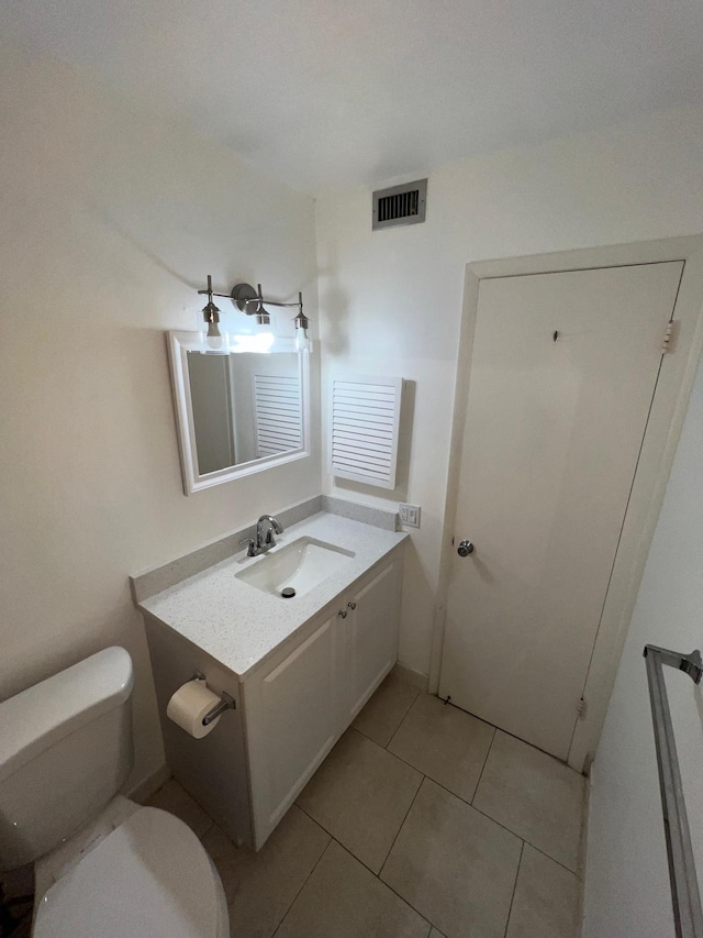 half bath with toilet, vanity, visible vents, and tile patterned floors