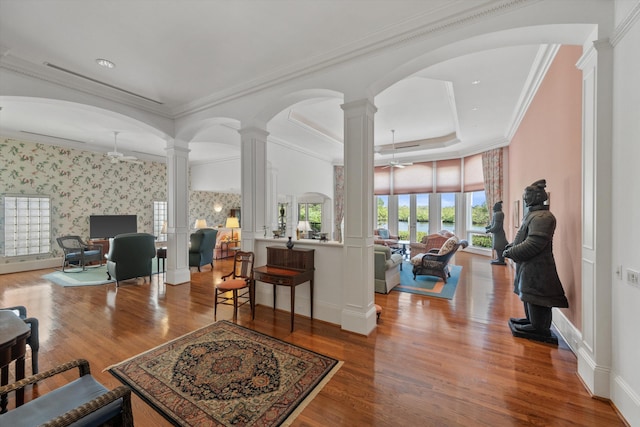 living room with wood-type flooring, ornamental molding, and ornate columns