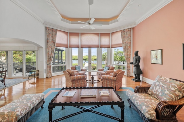 living room with crown molding, light hardwood / wood-style floors, french doors, ceiling fan, and a tray ceiling