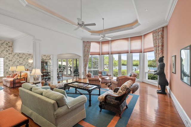 living room featuring ornamental molding, a tray ceiling, and ornate columns