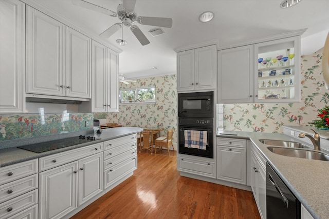 kitchen with black appliances, white cabinetry, and sink