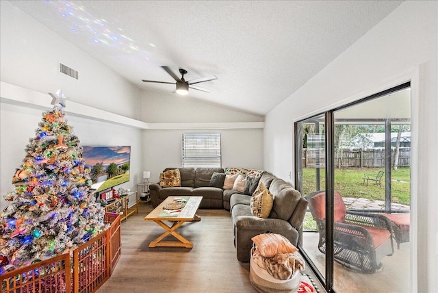 living room featuring a textured ceiling, hardwood / wood-style flooring, vaulted ceiling, and ceiling fan