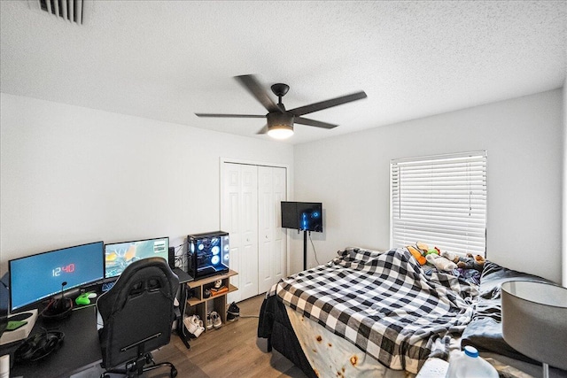 bedroom featuring hardwood / wood-style floors, a textured ceiling, a closet, and ceiling fan