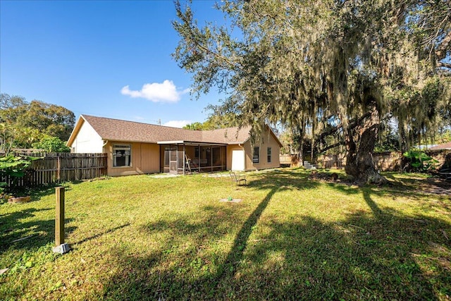 rear view of property featuring a sunroom and a yard