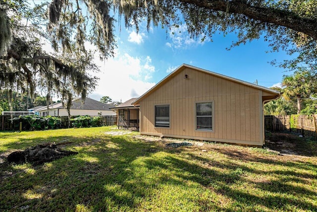 rear view of house featuring a yard and a sunroom