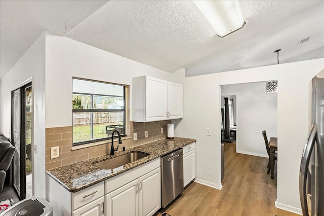 kitchen featuring sink, dark stone counters, lofted ceiling, white cabinets, and appliances with stainless steel finishes