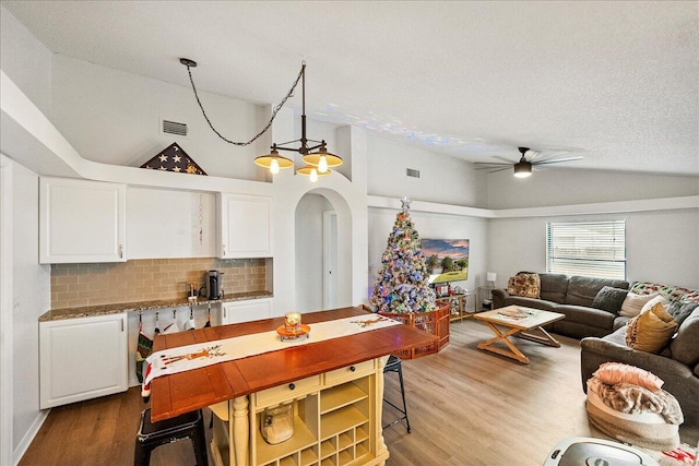 kitchen with tasteful backsplash, white cabinetry, and high vaulted ceiling