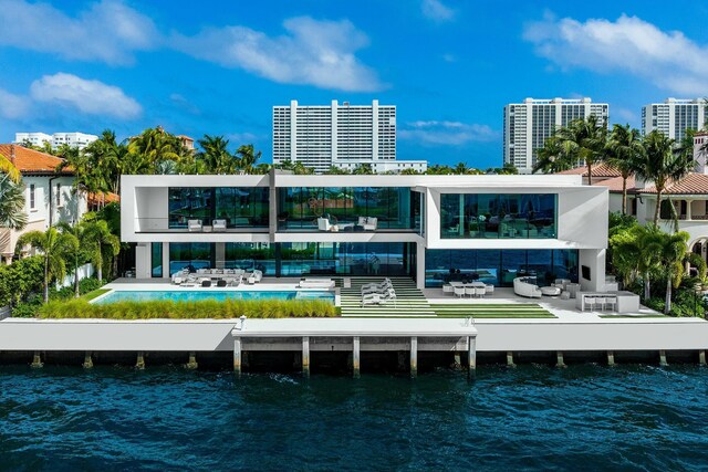 back house at dusk featuring an outdoor living space, a water view, a balcony, and a patio