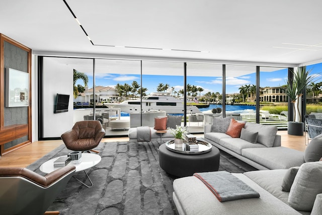 living room with light wood-type flooring, a water view, and expansive windows