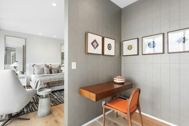 bedroom with light hardwood / wood-style floors and tile walls