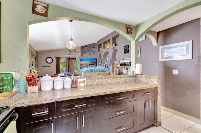 kitchen featuring light stone countertops, tasteful backsplash, pendant lighting, lofted ceiling, and light tile patterned floors