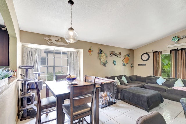 tiled dining room with a textured ceiling, plenty of natural light, and lofted ceiling