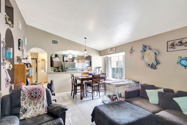 living room featuring ceiling fan, light tile patterned flooring, lofted ceiling, and a textured ceiling