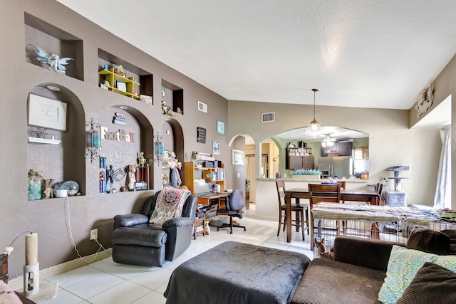 living room featuring built in features, light tile patterned floors, and vaulted ceiling