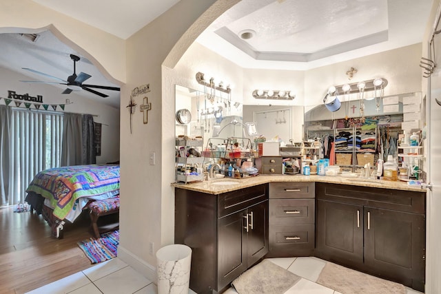 bar featuring light tile patterned flooring, dark brown cabinetry, ceiling fan, and sink