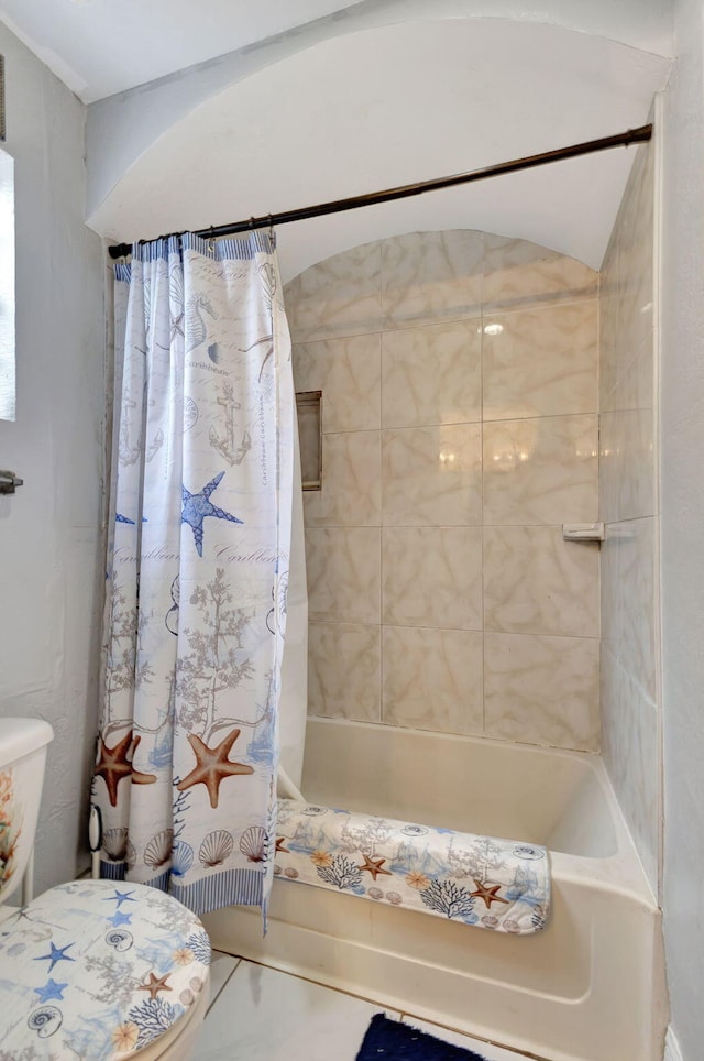 bathroom featuring tile patterned floors, toilet, and shower / bath combo with shower curtain