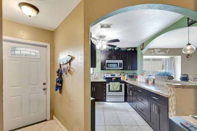 kitchen with a textured ceiling, stainless steel appliances, ceiling fan, decorative light fixtures, and light tile patterned flooring