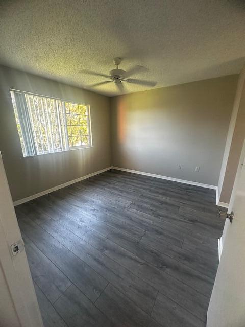 spare room with ceiling fan, dark wood-type flooring, and a textured ceiling