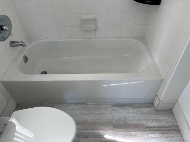 bathroom featuring a washtub and toilet