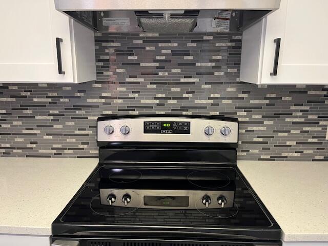 kitchen featuring white cabinets, ventilation hood, tasteful backsplash, and stainless steel electric range