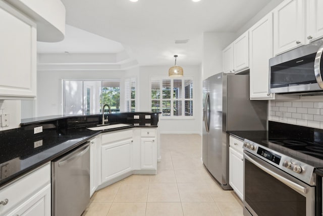 kitchen featuring sink, stainless steel appliances, white cabinets, dark stone counters, and light tile patterned flooring