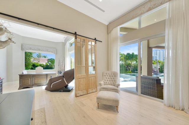 living area with a barn door and light hardwood / wood-style floors