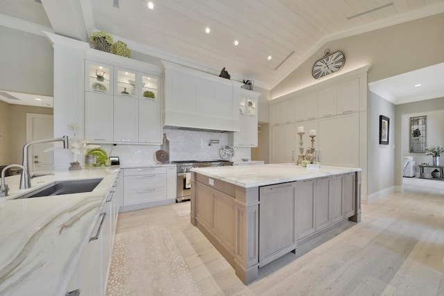 kitchen featuring white cabinetry, sink, light stone counters, decorative backsplash, and stainless steel stove