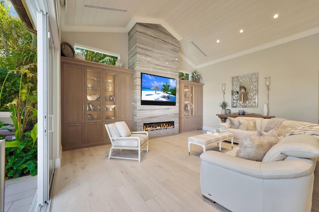 living room with high vaulted ceiling, light hardwood / wood-style floors, ornamental molding, and a high end fireplace