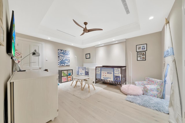 bedroom featuring a tray ceiling, ceiling fan, and light hardwood / wood-style flooring