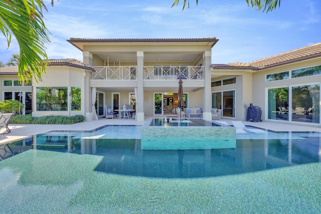 rear view of property featuring a balcony and a patio