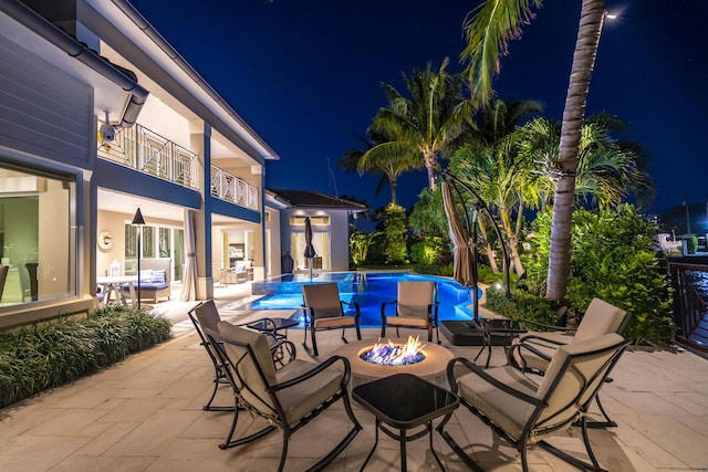 patio at twilight featuring a fire pit and a balcony